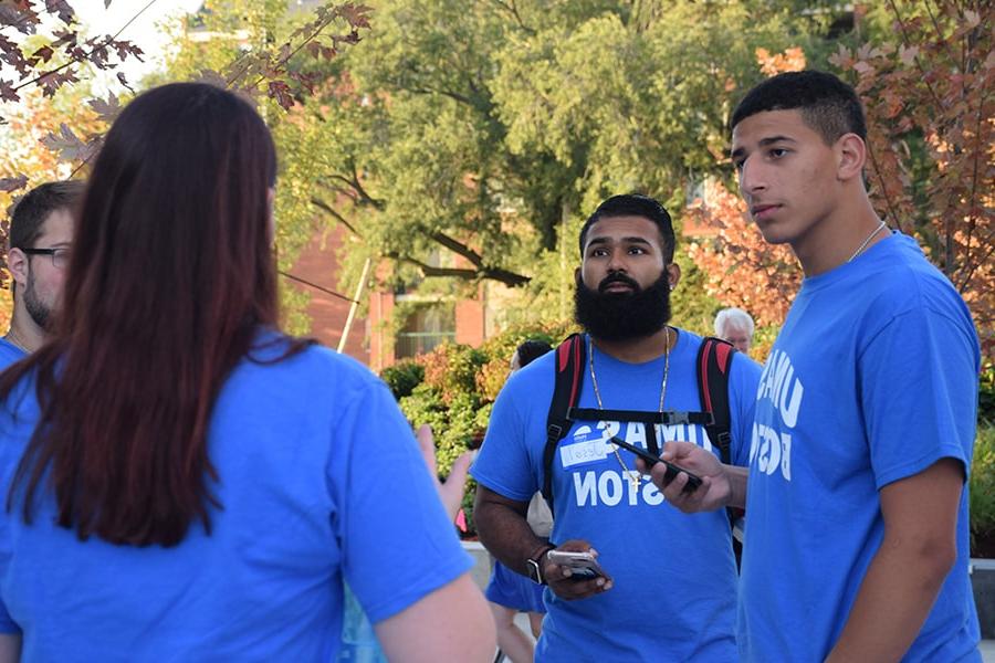 Students in 马塞诸斯州大学的 Boston t-shirts talking on move-in day by residence halls.